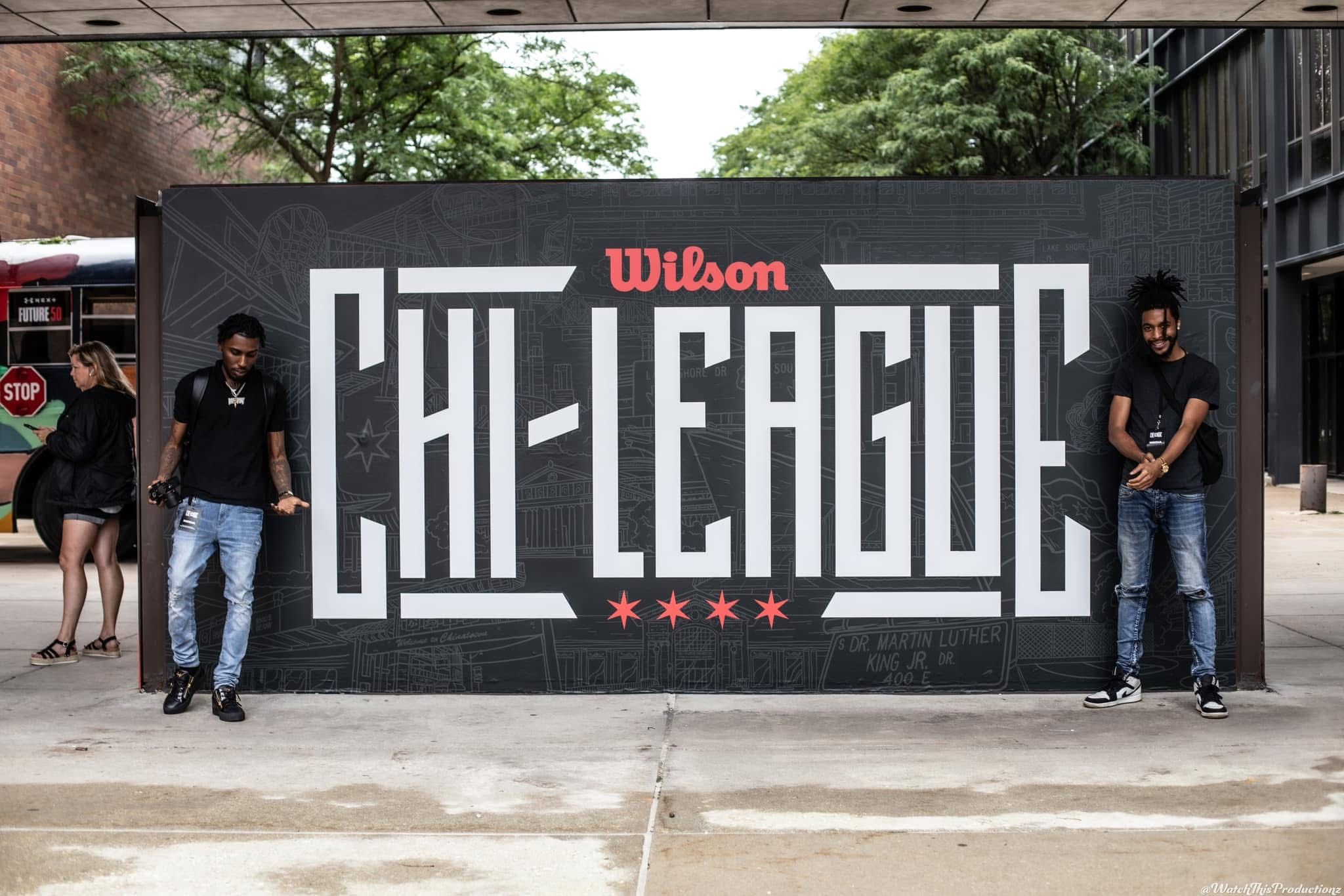 Wilson Cal-League logo displayed on black wall with event staff standing on either side.