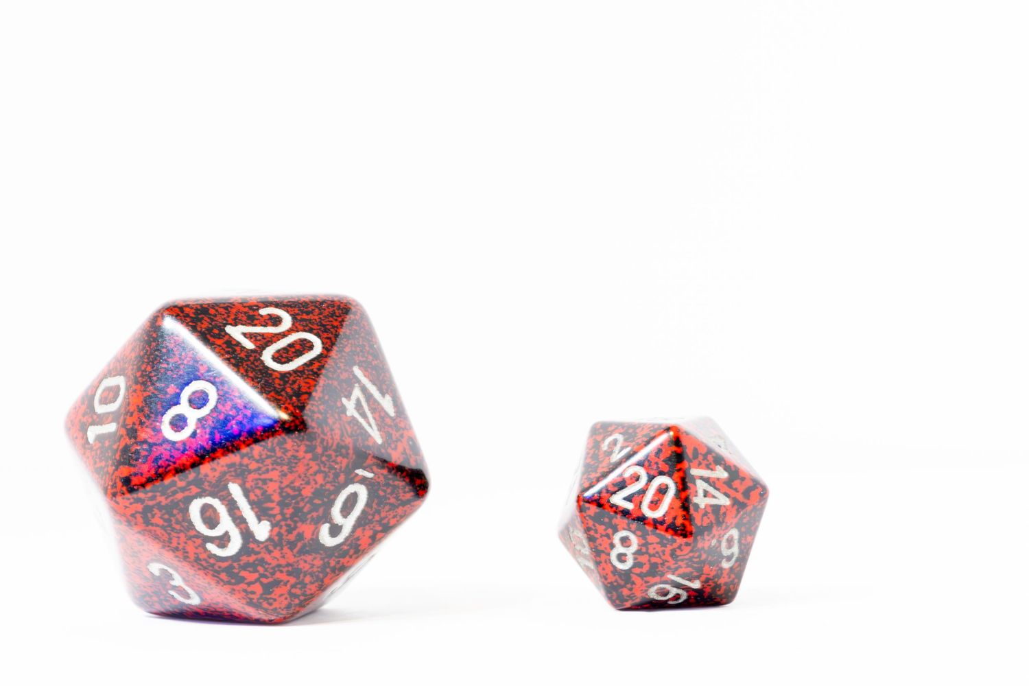 A pair of red D20 DND playing dice one on the left is larger than the one on the right.