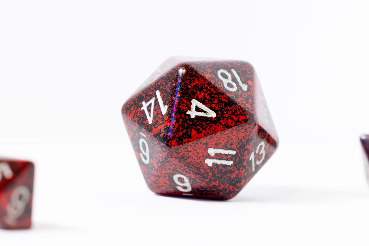 A set of red DND playing dice on a white table top with white background. The Dyson arranged where different dice are in and out of focus.