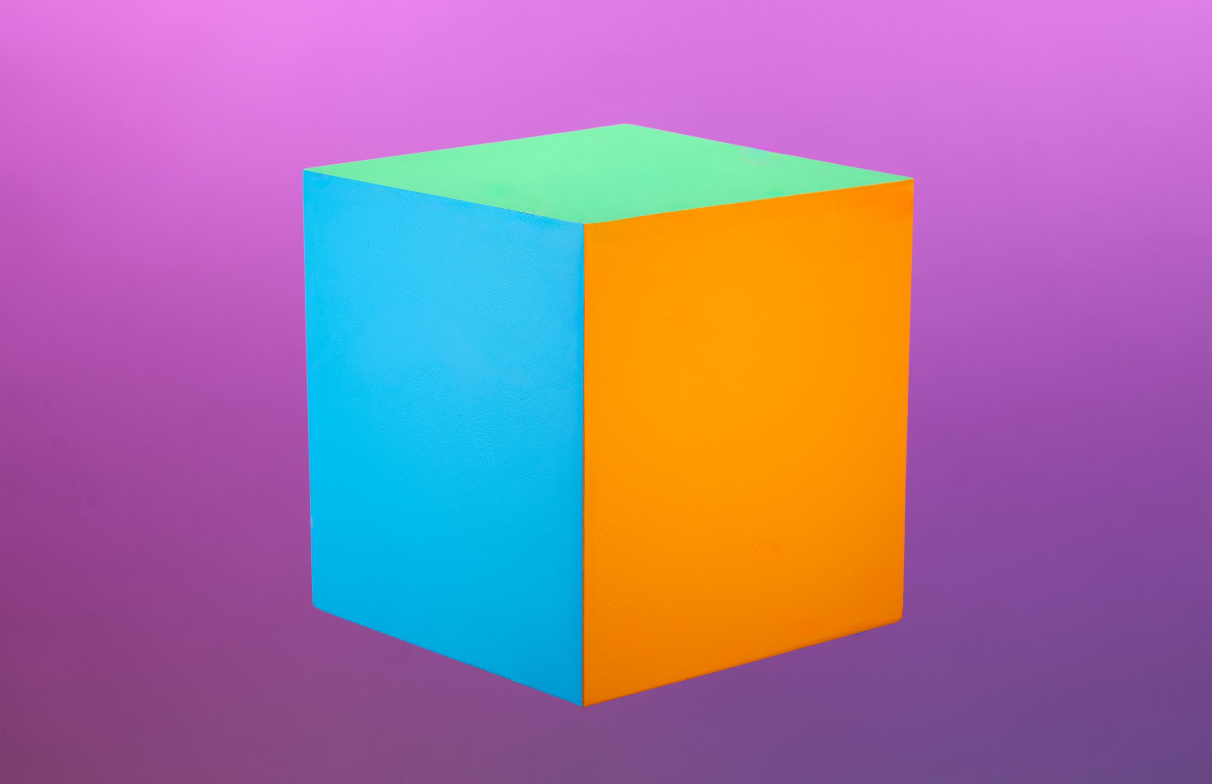 Bright cube with turquoise, orange, and green sides against a purple background.