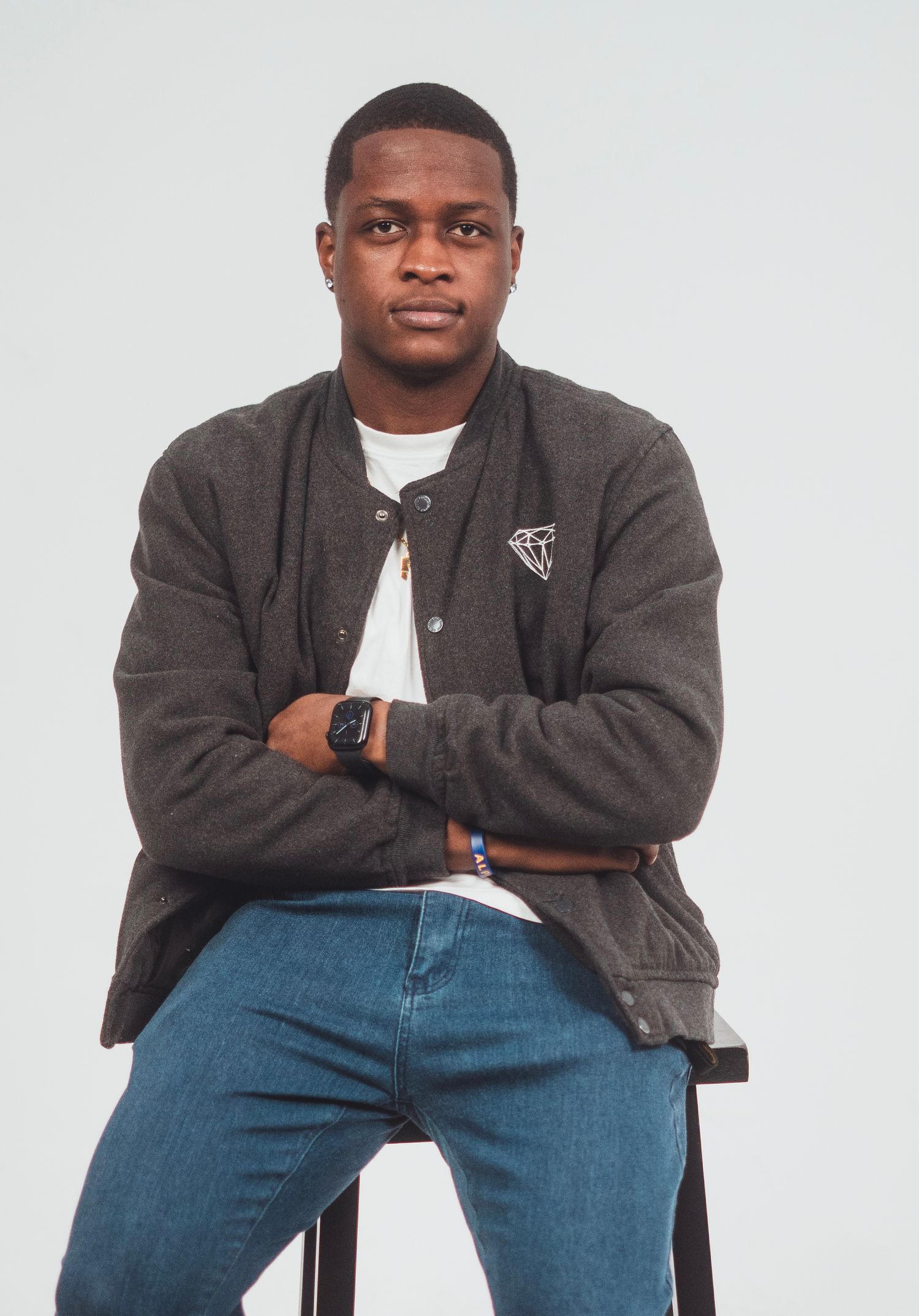 A casual portrait series showing poses in a gray jacket and jeans while seated on a chair.