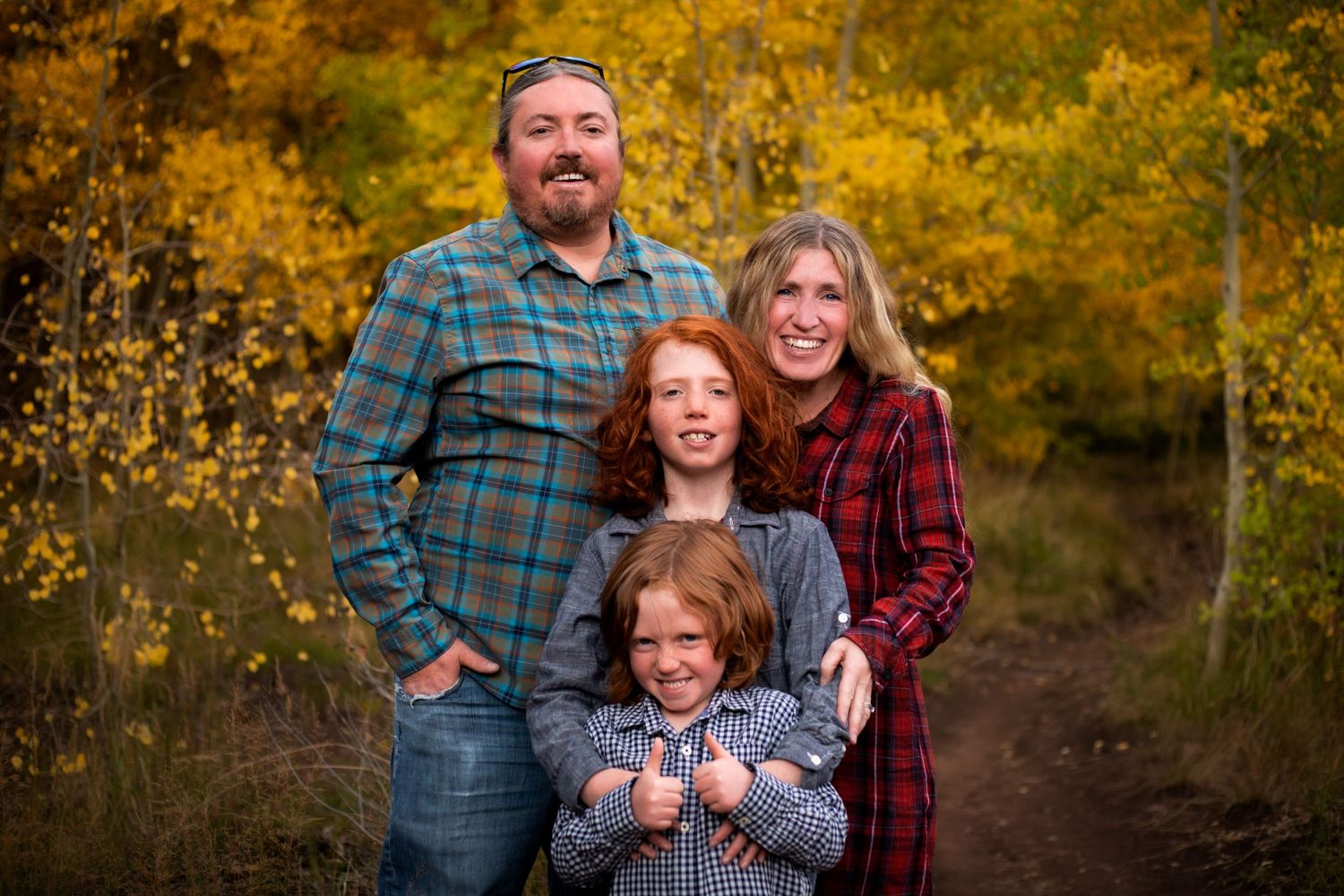 A mom and dad stand behind their two sons while they all smile at the camera in Breckenridge, Colorado