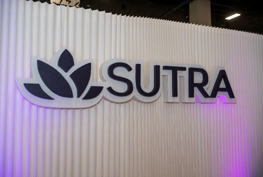 Purple-lit Sutra logo display at a corporate event or retail space.