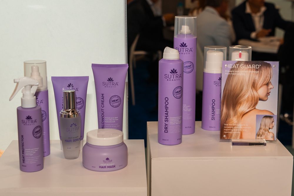 Purple hair care product bottles and containers displayed on white surface with marketing materials and packaging.