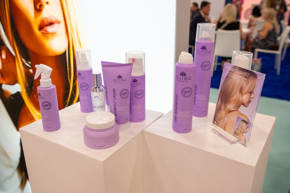 Row of purple beauty product bottles displayed with marketing materials on white retail shelving.