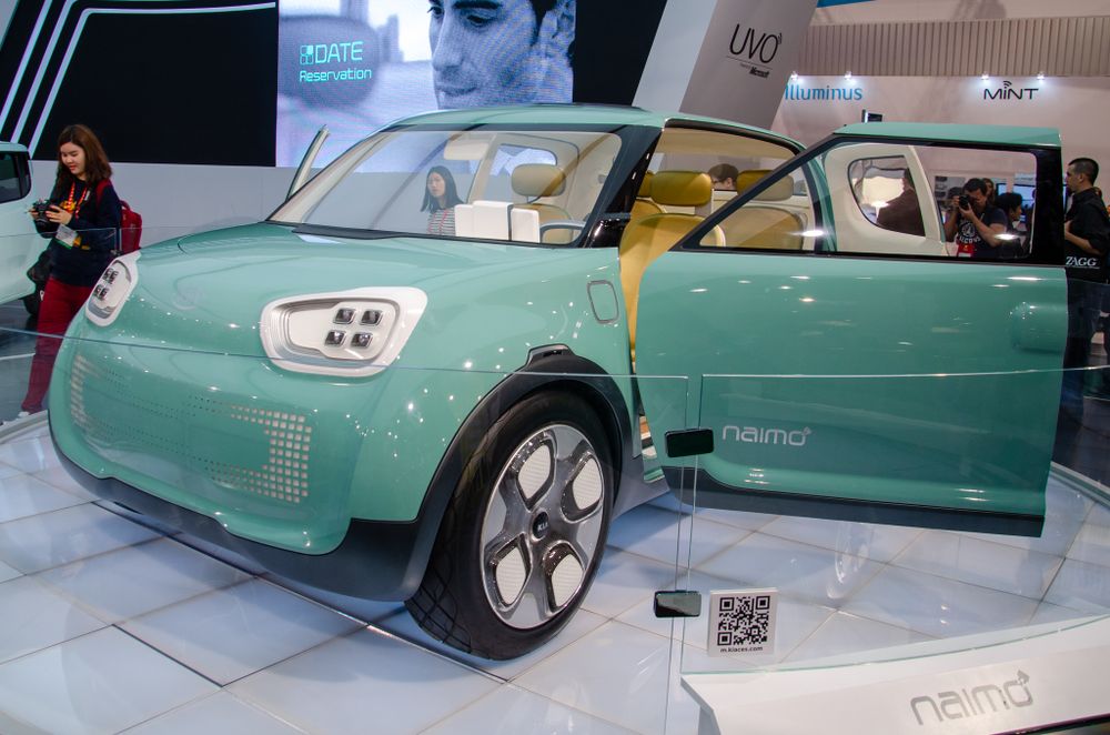 Mint green concept car with futuristic design features on showroom floor.