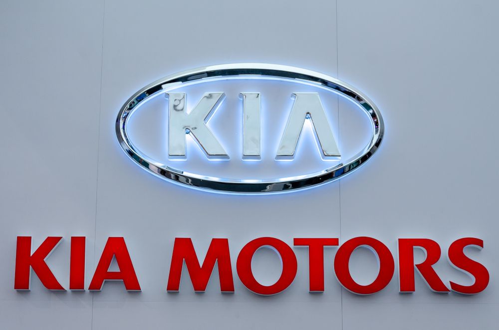 Row of illuminated Kia Motors corporate logo signs on display.