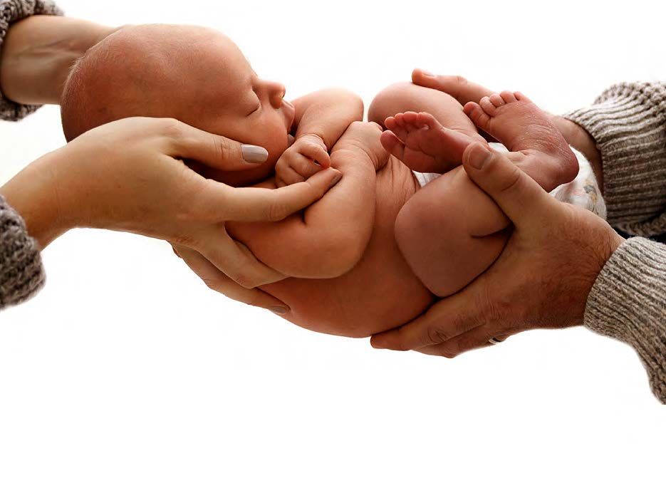Close-up of hands holding tiny baby feet with gentle care in a warm, intimate moment.