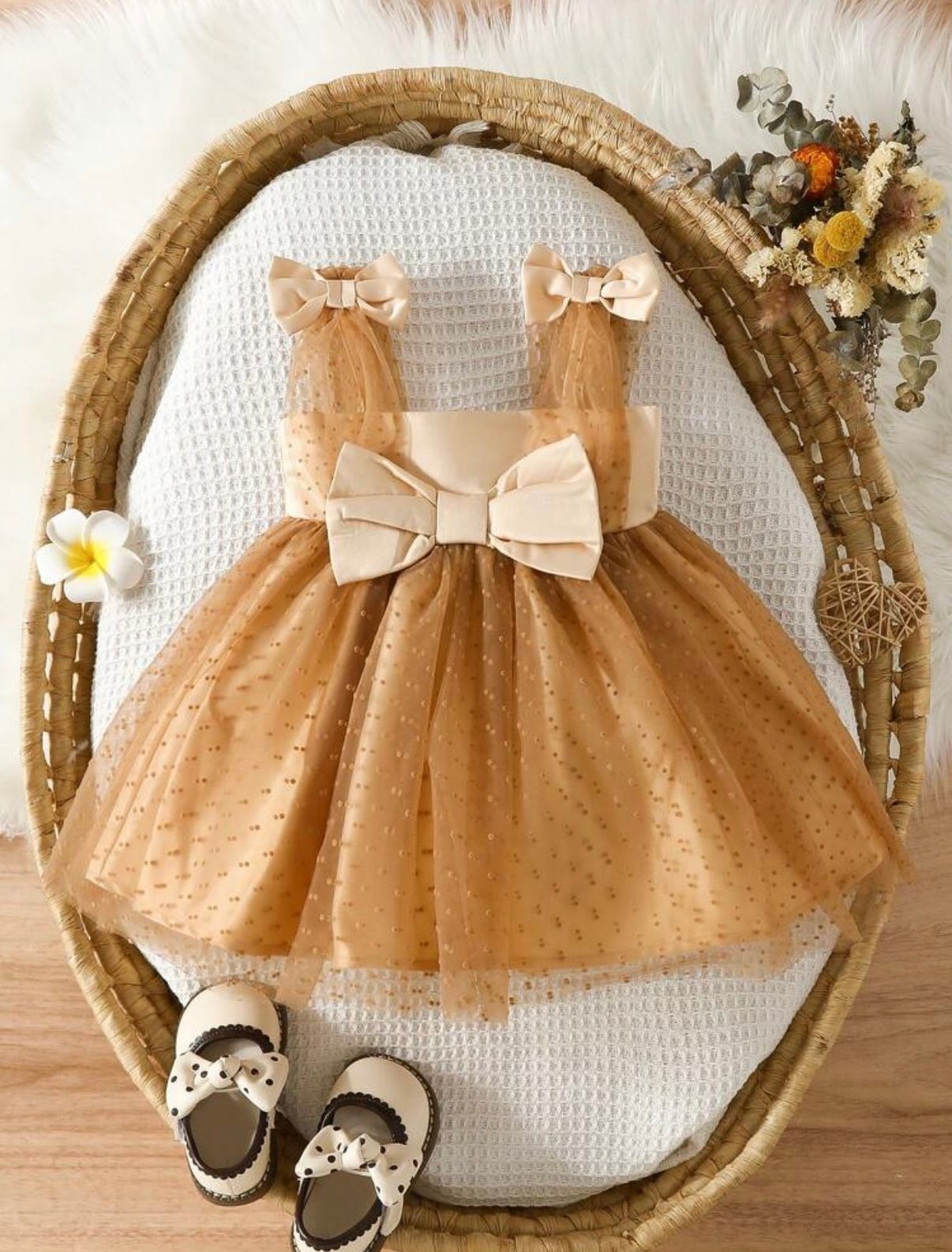 Peach tulle dress with bow detail and matching shoes arranged on wooden display.