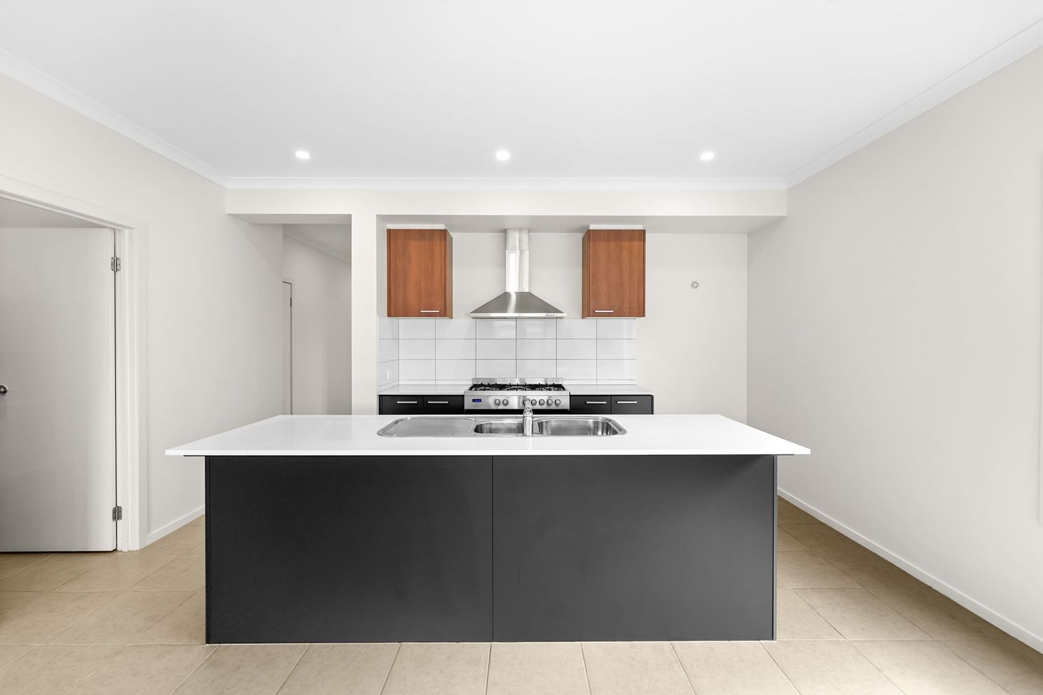 Contemporary kitchen featuring dark gray island counter, white quartz countertop, and wooden upper cabinets with range hood.
