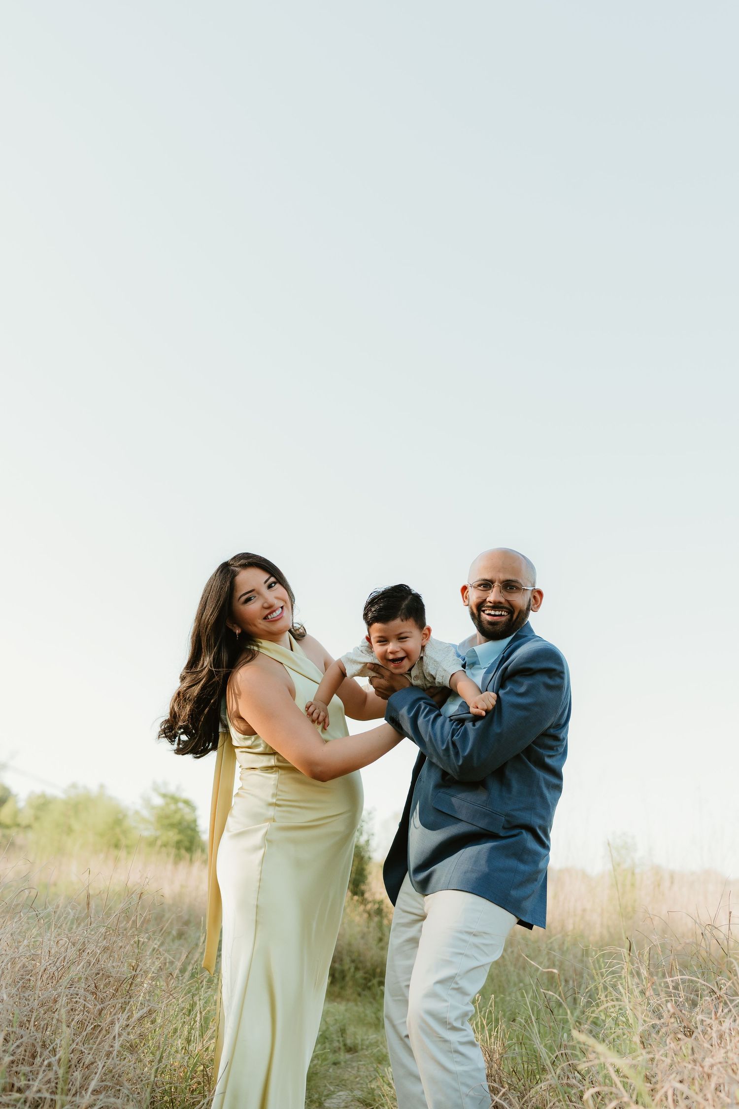 Playful couple laughing and dancing together in a sunny field.