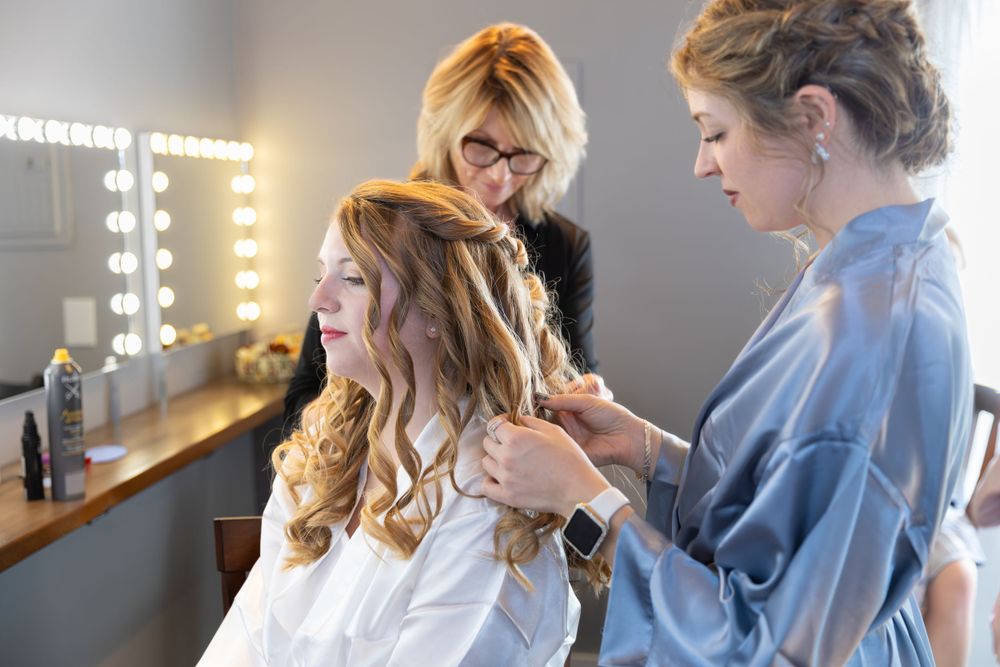 Behind the scenes of bridal hair styling in preparation room with vanity lights.