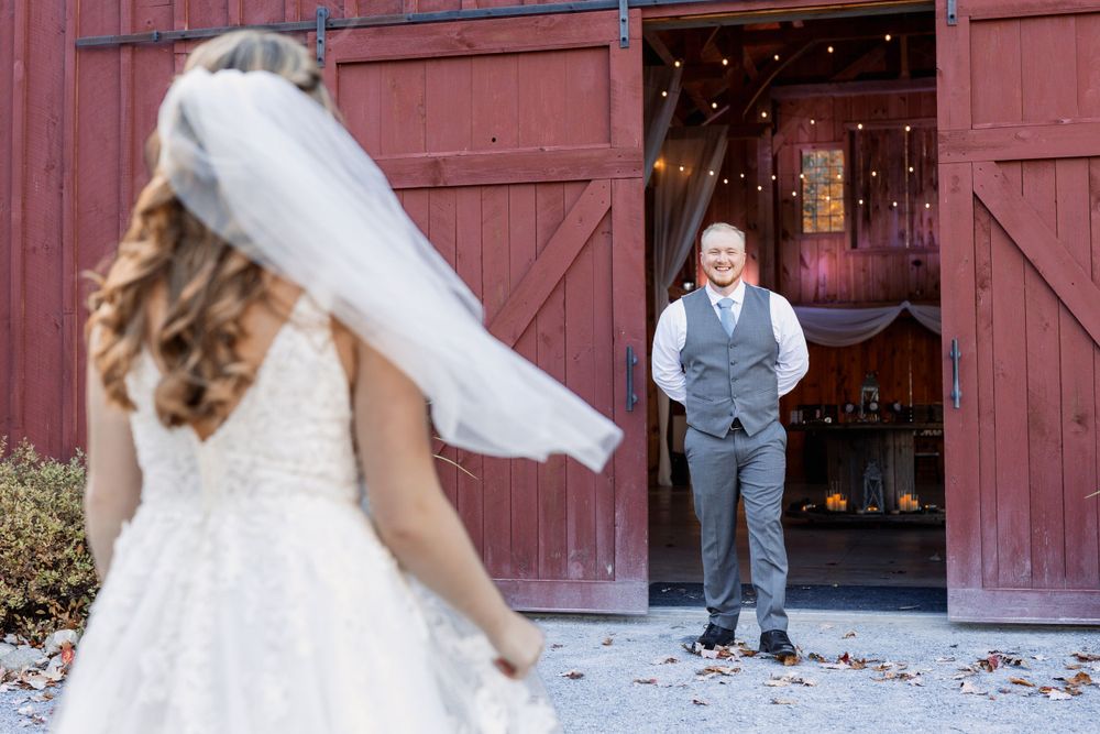 First look moment at rustic red barn with confetti falling.