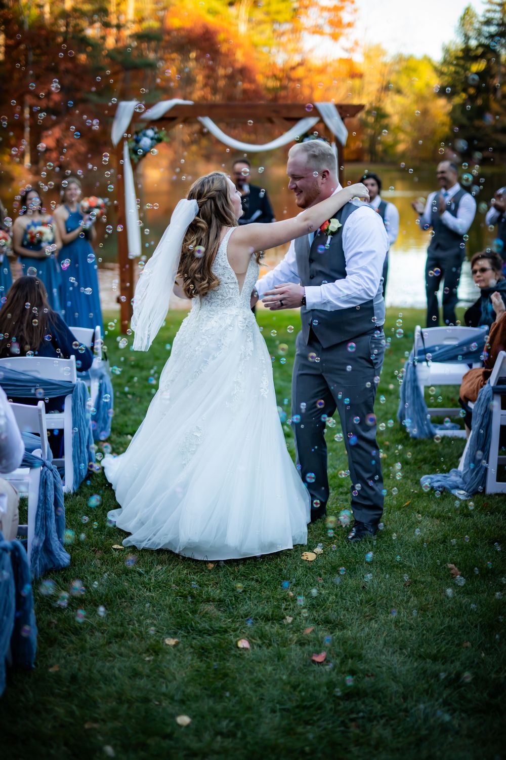 Newlyweds share first dance under outdoor arch with confetti falling.