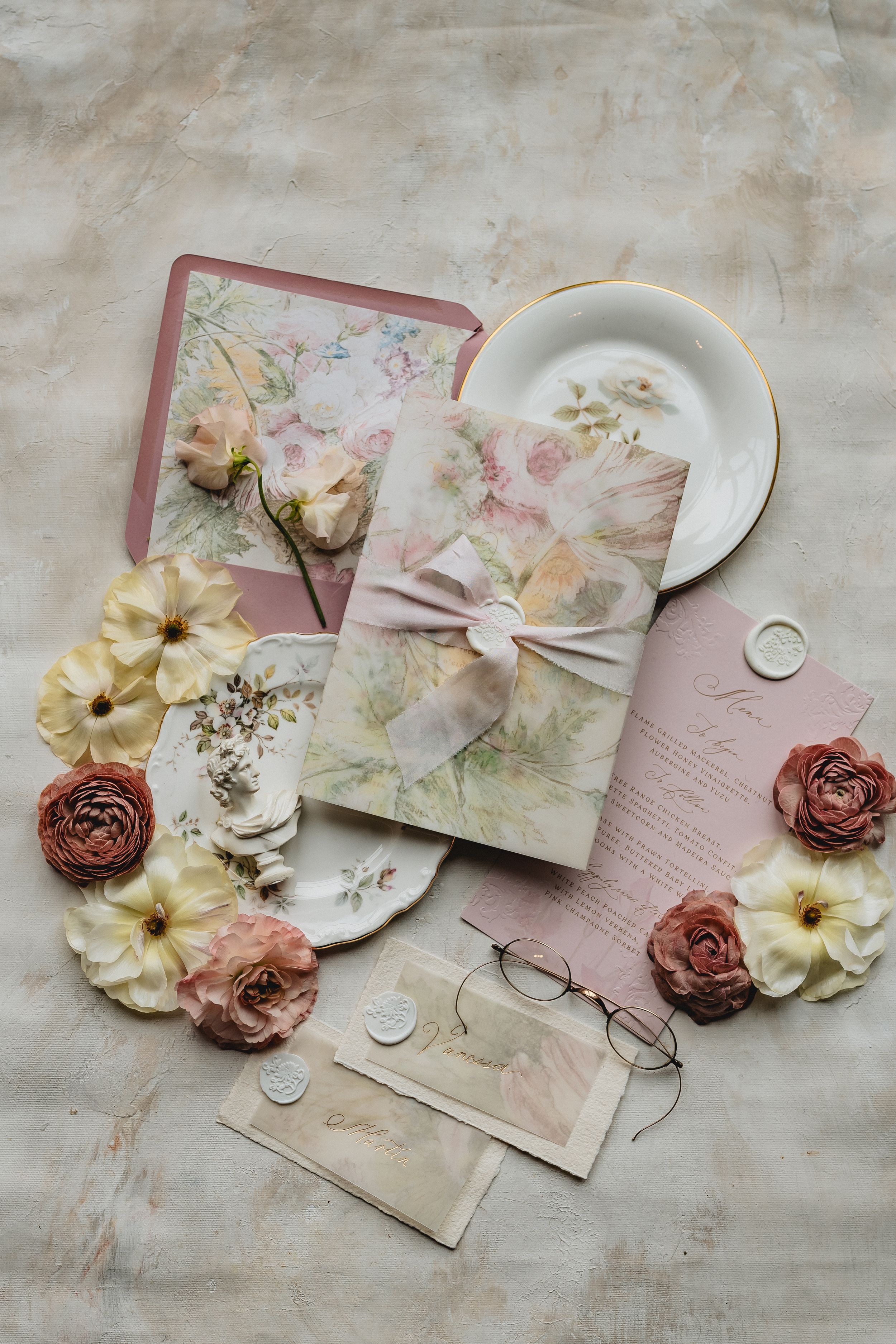 Vintage floral wedding invitation suite with pink roses, cream daisies and delicate stationery on textured linen background.