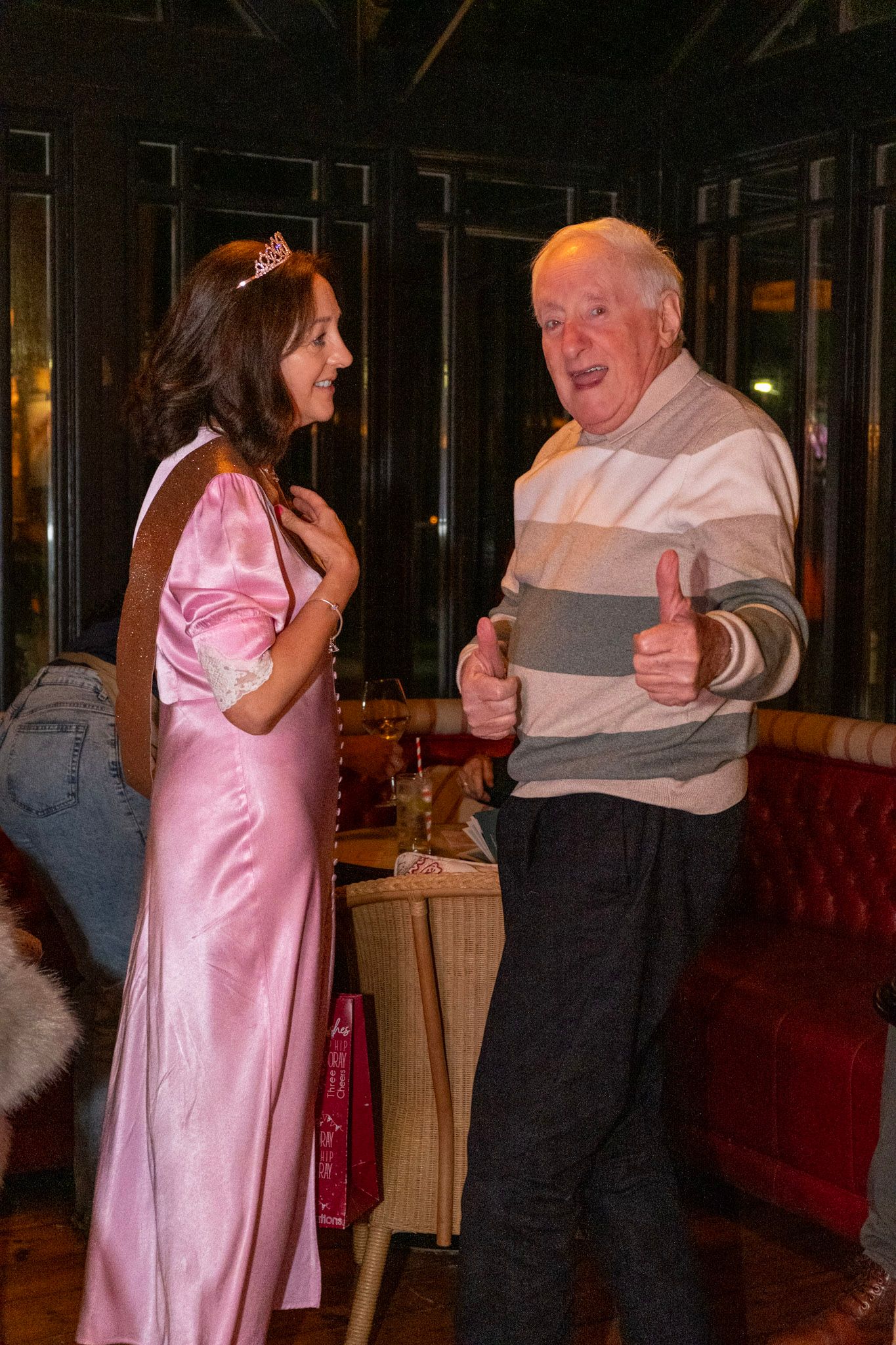 Party scene with person in pink dress chatting with guest in striped sweater.
Dublin, Ireland.