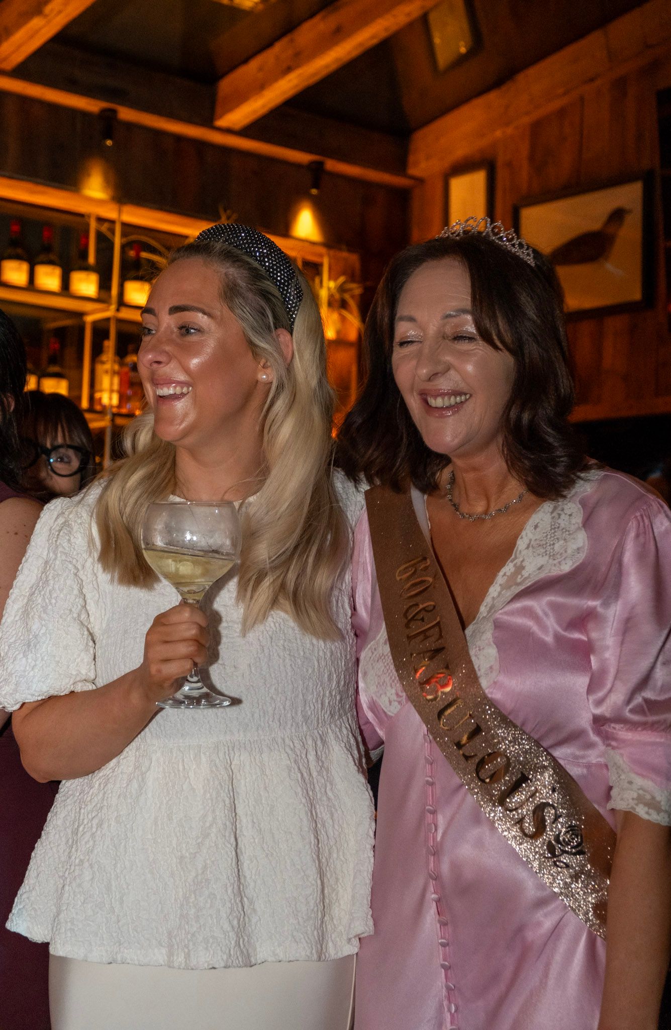 Two celebratory guests share laughter while holding wine at festive event.
Dublin, Ireland.
