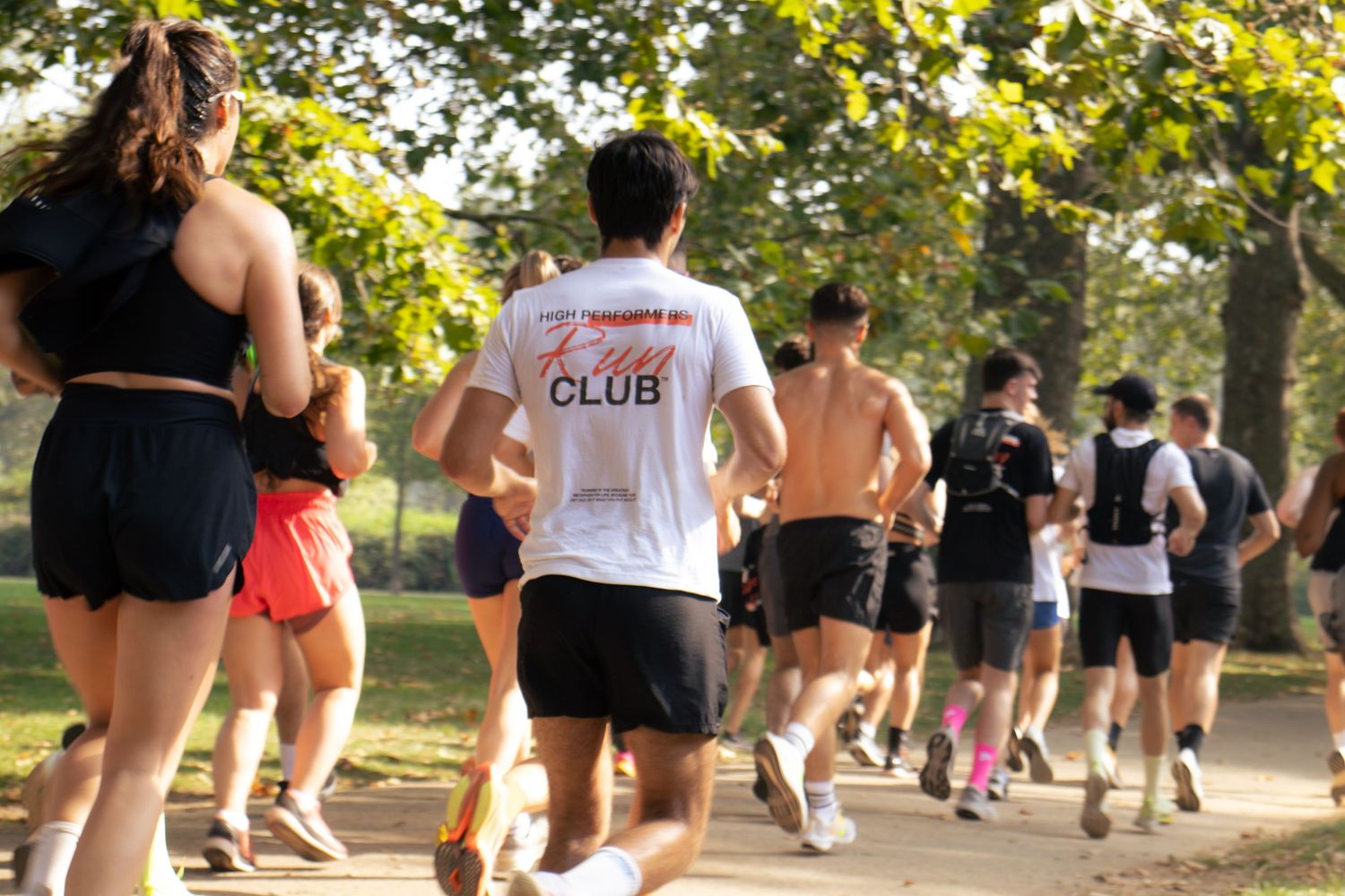 Running club members exercising together on a tree-lined path in the summer sun.