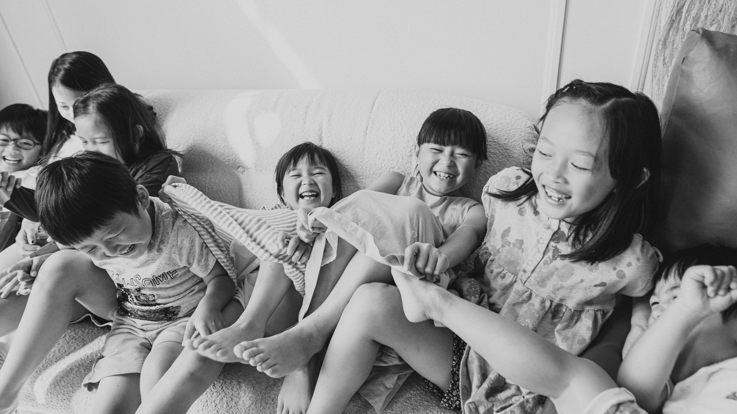 A black and white photograph shows a group of children sitting together and laughing joyfully.