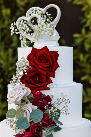Elegant white wedding cake adorned with red roses from a wedding in Phoenix Ariziona