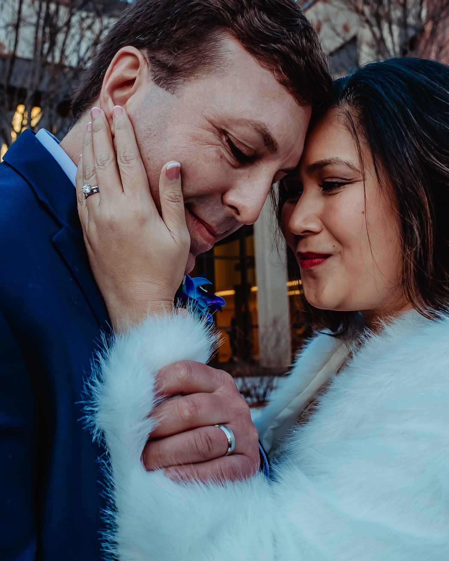 A romantic moment captured between a couple in winter, with the person in blue suit and other in white fuzzy coat.