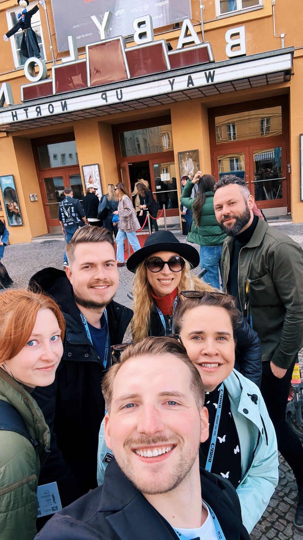 A group of friends taking a selfie together outside the Alamo Drafthouse Cinema on a city street.