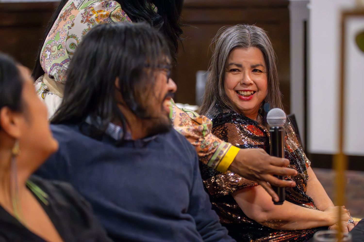 A panel discussion with speakers using microphones sharing animated conversations at a cultural event.
