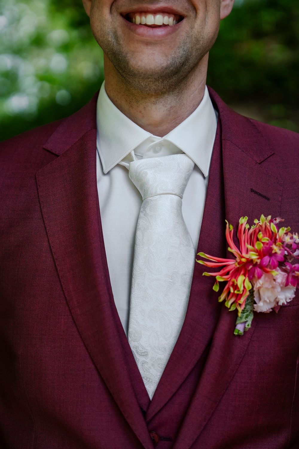 Close-up trouwfoto van bruidegom met stropdas en corsage.