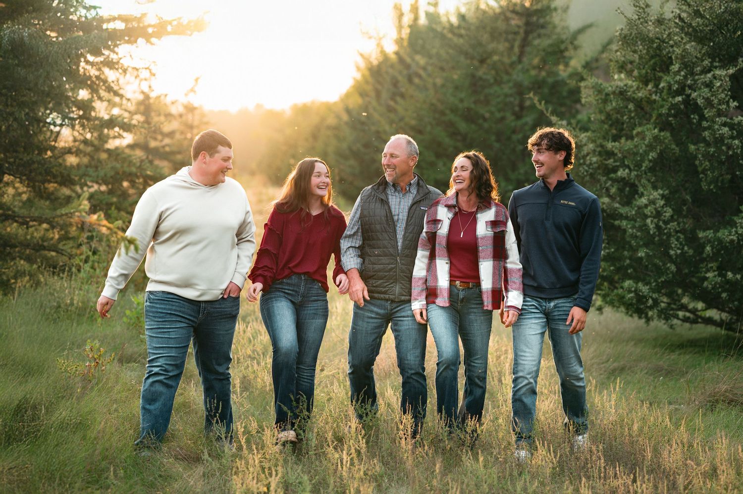 Outdoor family portrait with parents and young adults walking together in golden light with warm film-inspired edits in Brookings SD.
