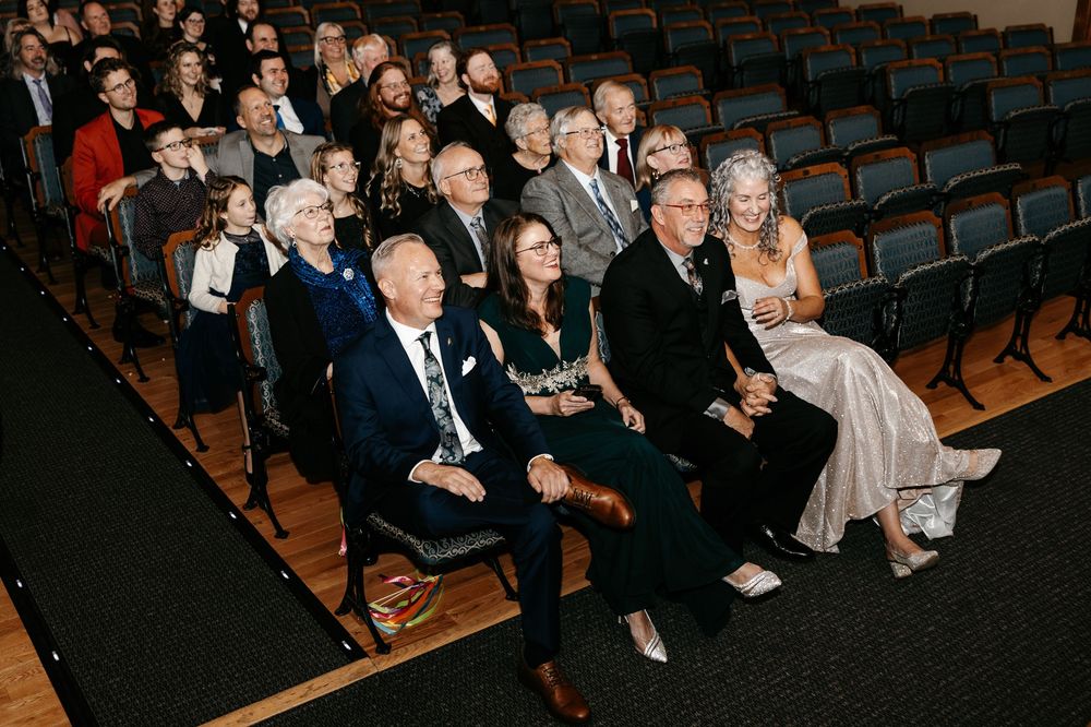 Formally dressed audience members seated in theater rows during an elegant evening event.