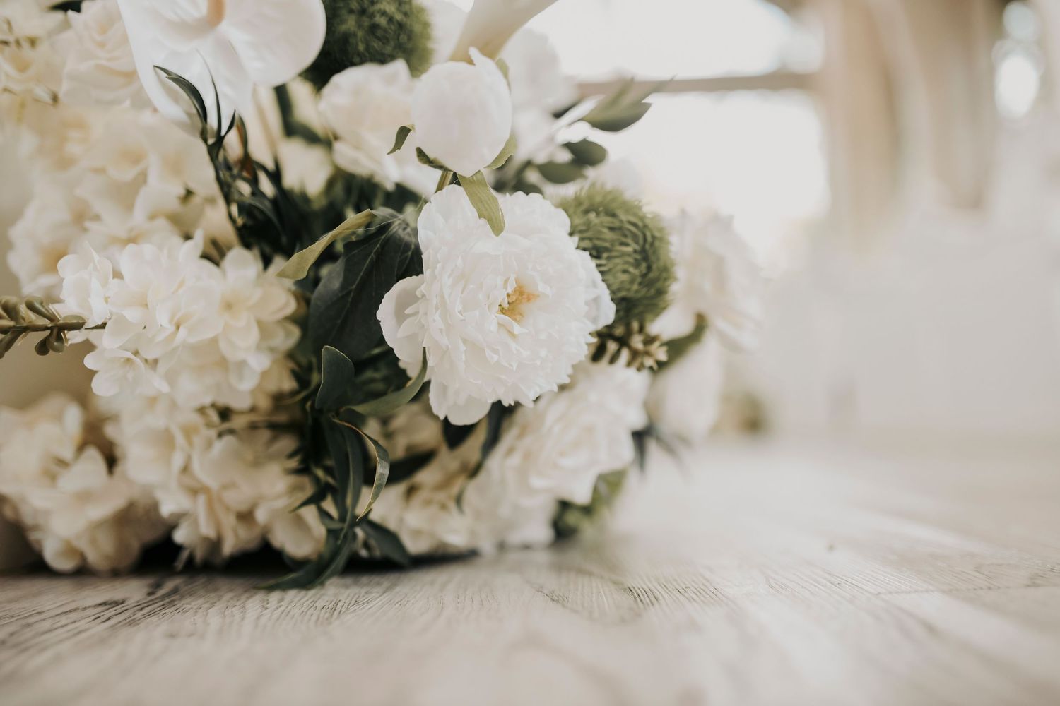 Elegant wedding ceremony space featuring white wooden pews and hanging florals