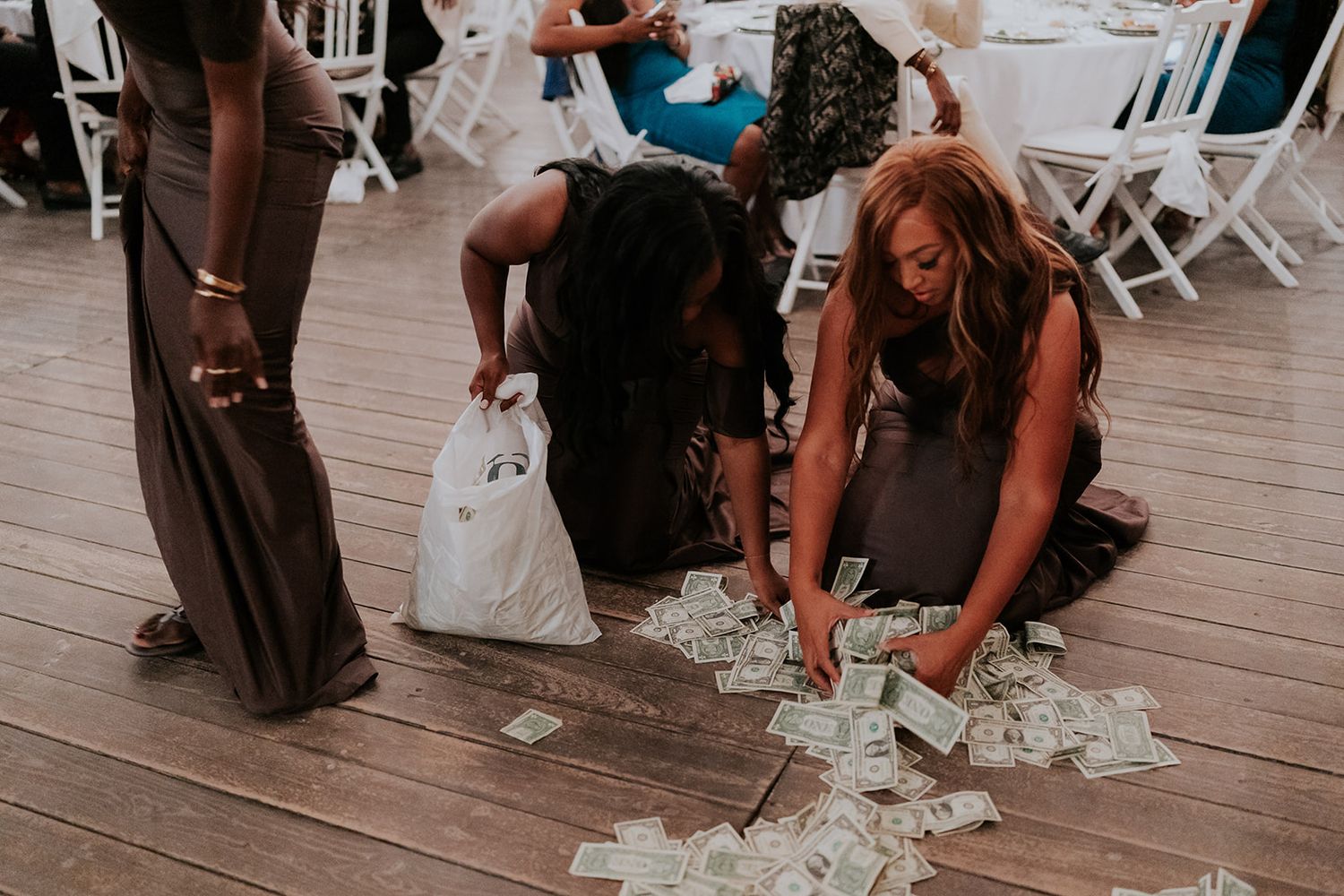 Wedding guests gathering puzzle pieces off a wooden deck during a reception activity.
