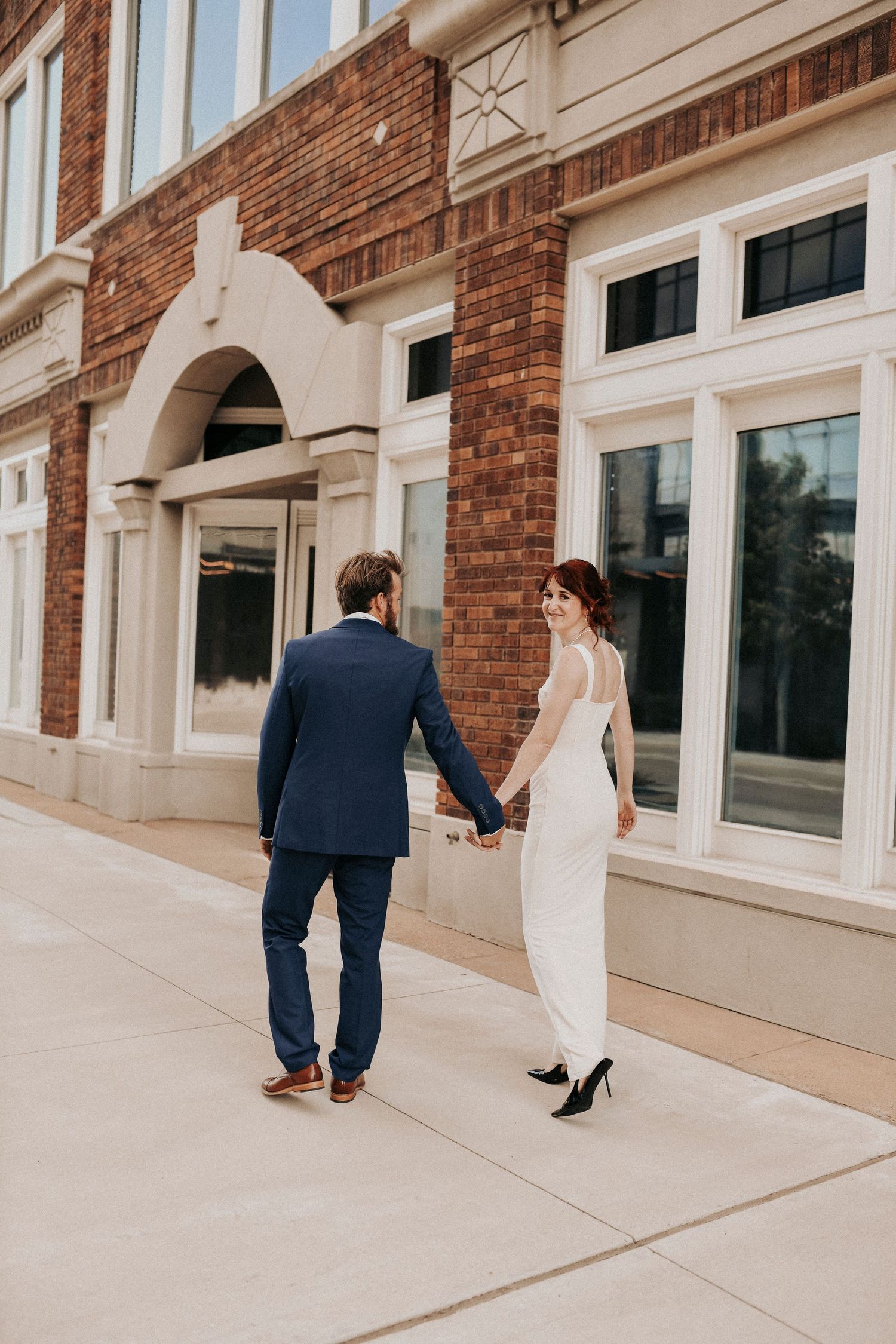 Engaged couple standing beneath arches at Dallas County Records Building