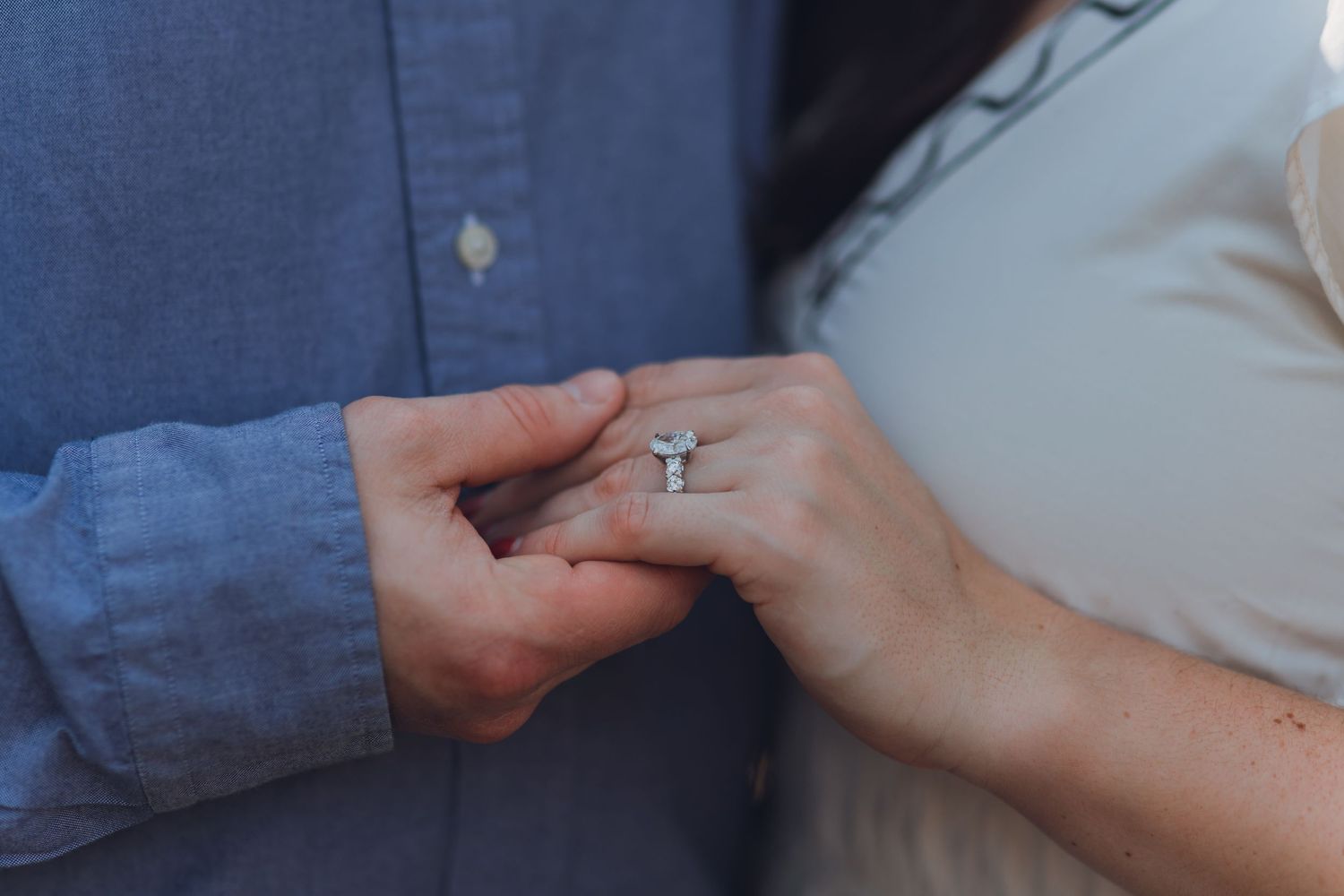 Close-up of couple holding hands showing a sparkling diamond engagement ring, romantic proposal moment.