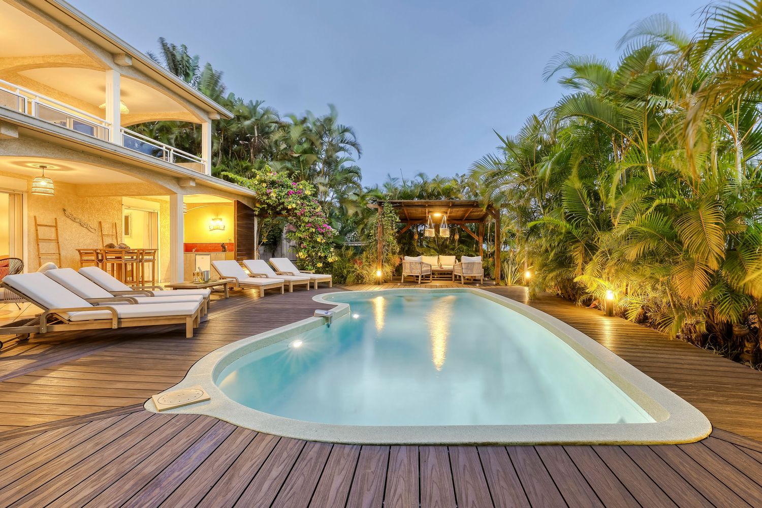 Elegant outdoor patio with pool, white furniture, and tropical landscaping at a luxury villa.