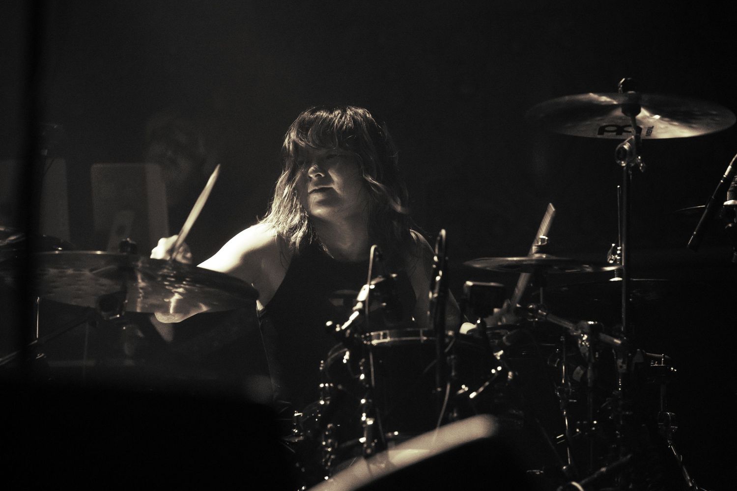 A black, yellow, and white photo of Tatsuya Amano, a Japanese drummer playing the drums for TK from Ling Tosite's concert at the Belasco LA