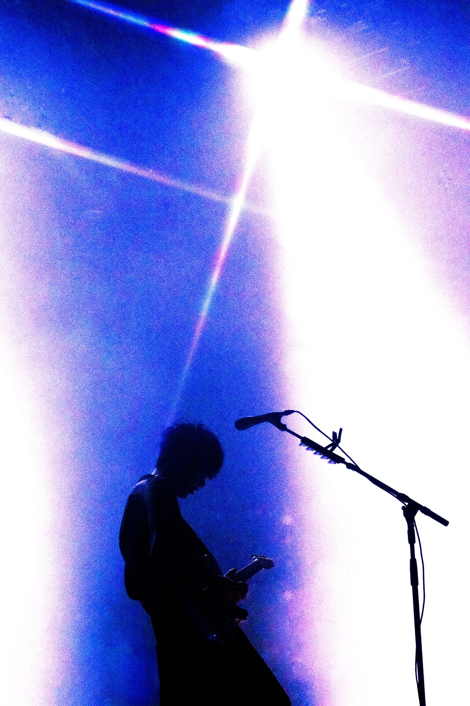 Y2K style edit of TK from Ling Tosite Sigure performing on stage, live at The Belasco. The photo has light beams, starburst, & a silhouette.
