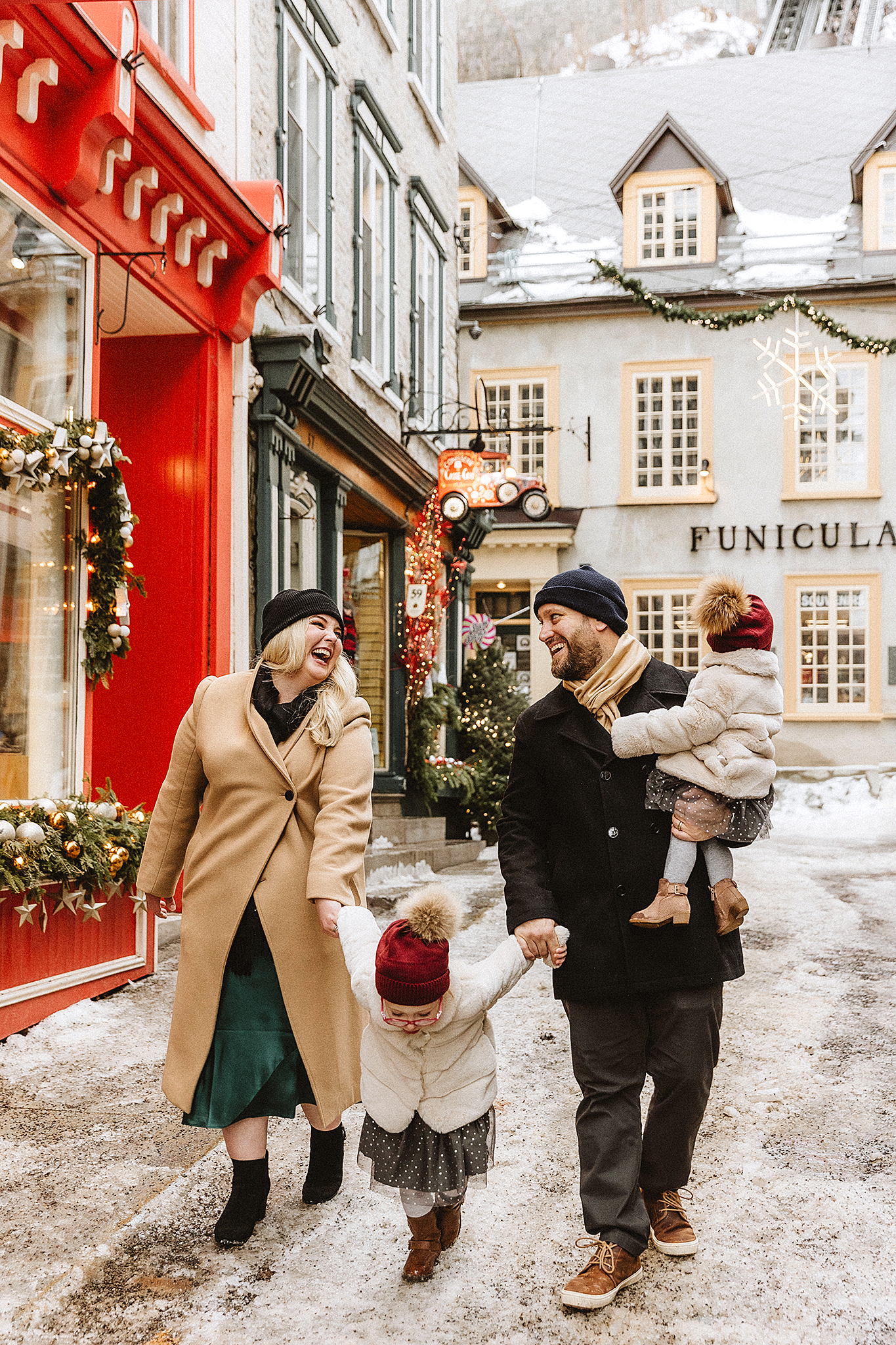 Winter street scene in historic Quebec City with red storefront and snow-covered buildings.