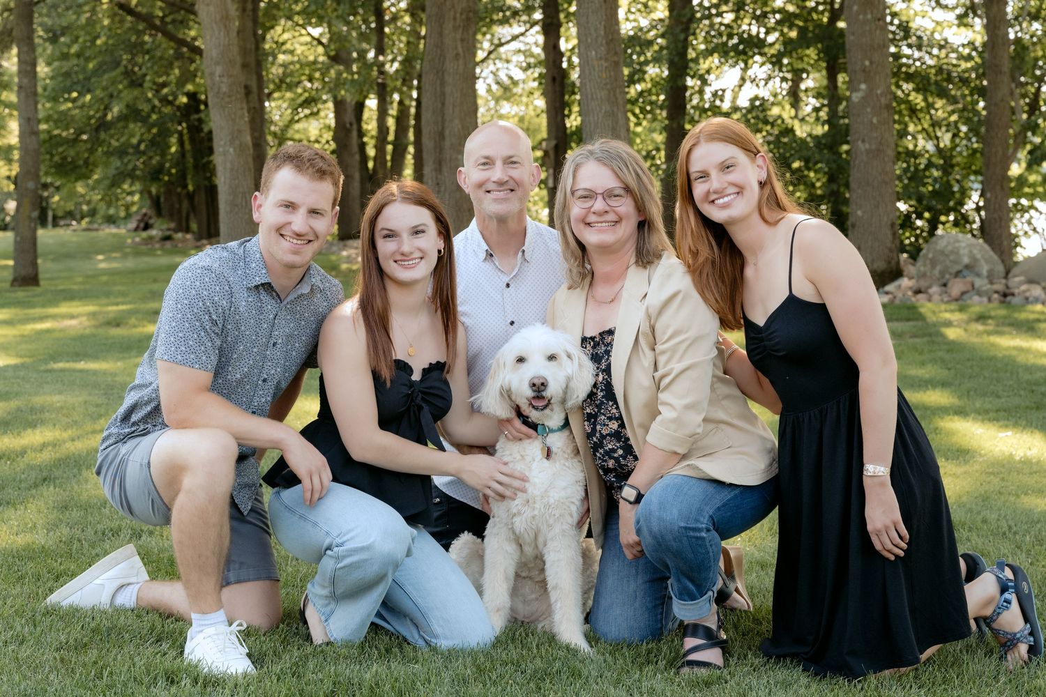 family kneeling for portrait with dog during summer family portraits at the cabin on lake wissota in chippewa falls wi