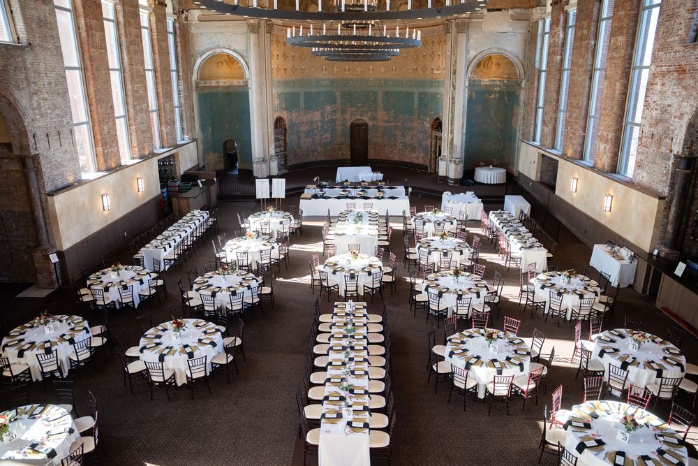 Elegant banquet hall in the Monastery Event Center with round white-clothed tables set for a large event in a historic brick building.