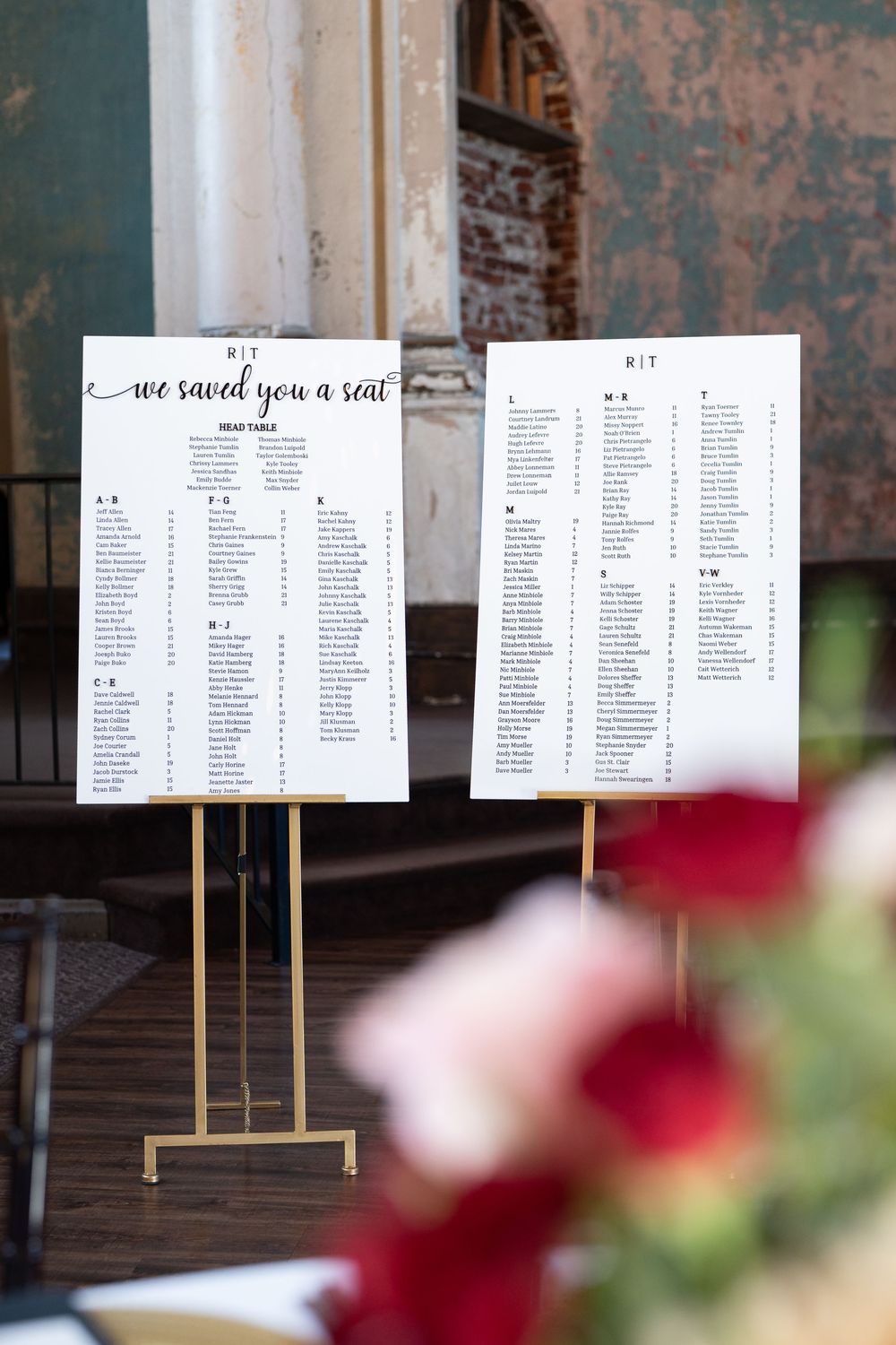 Elegant wedding seating chart on gold stands with 'we saved you a seat' script, displayed at a romantic venue.
