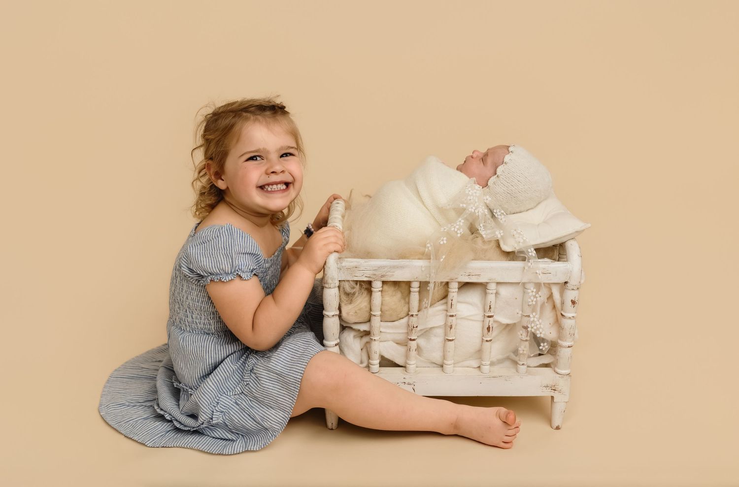 Proud big sister shows off her new baby, who slept in a spindle crib, captured by Charlottesville newborn and family photographer.