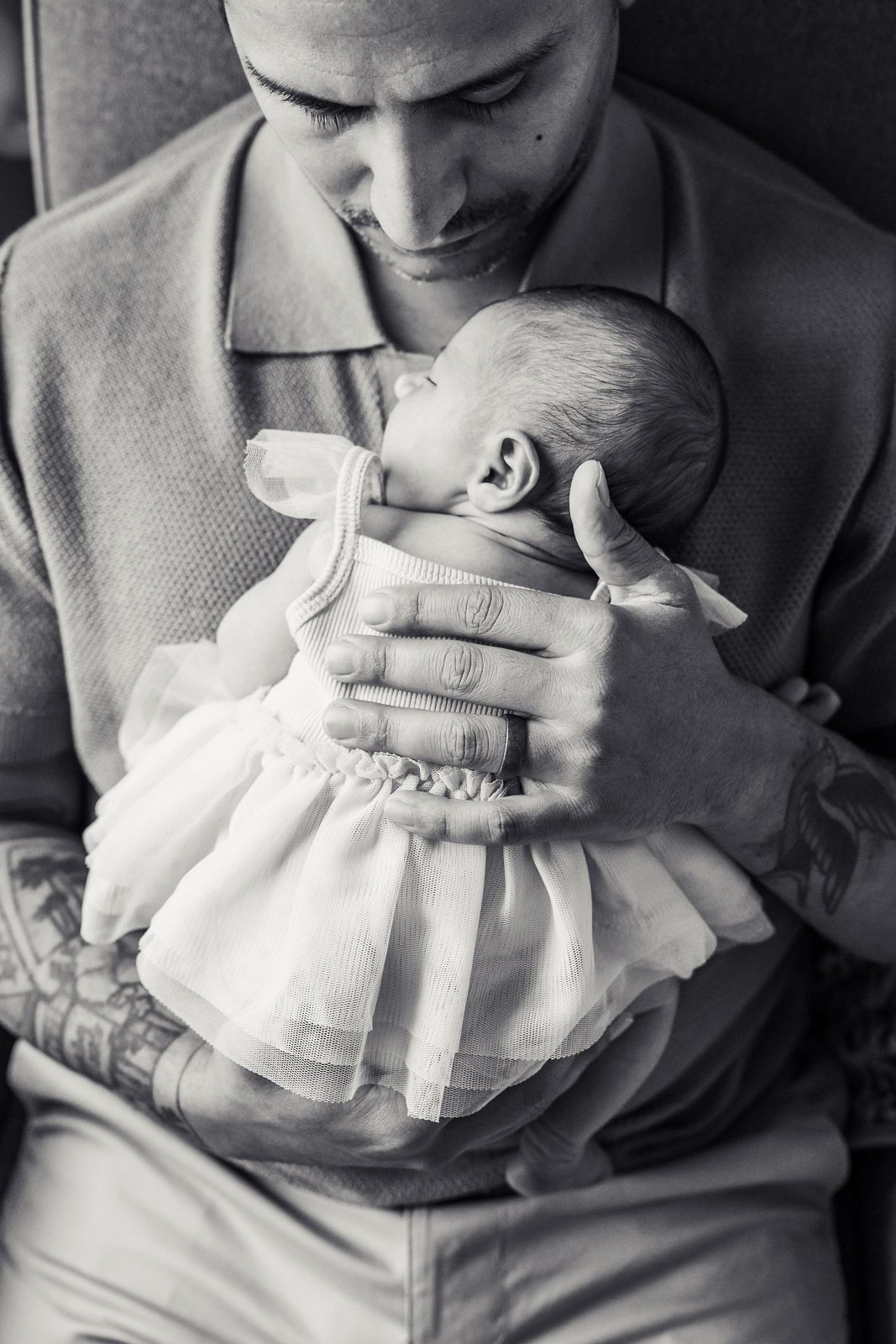 Black and white photo of dad holding sleeping newborn.