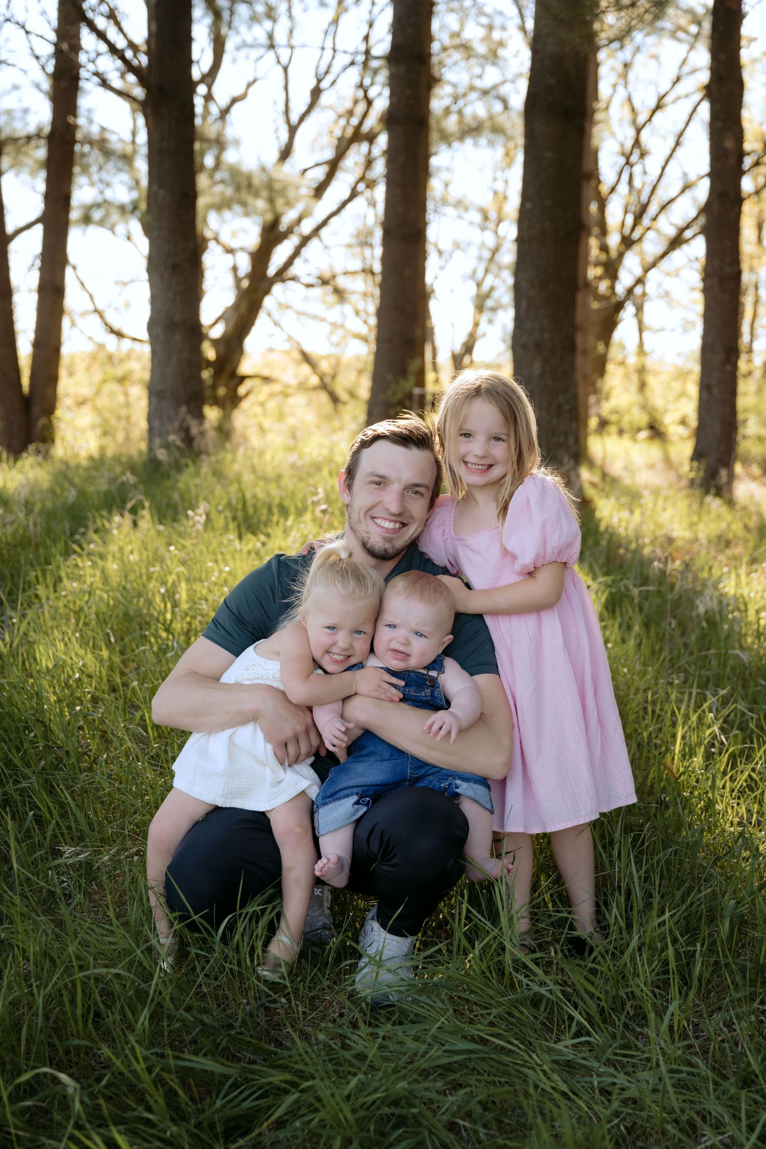 dad snuggles three kids during lifestyle outdoor spring portrait session in Hudson, WI