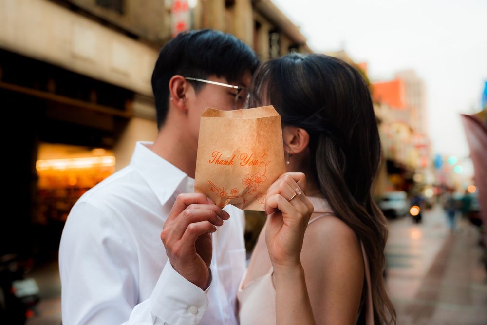 Couple sharing a romantic kiss behind a paper bag on a city street.