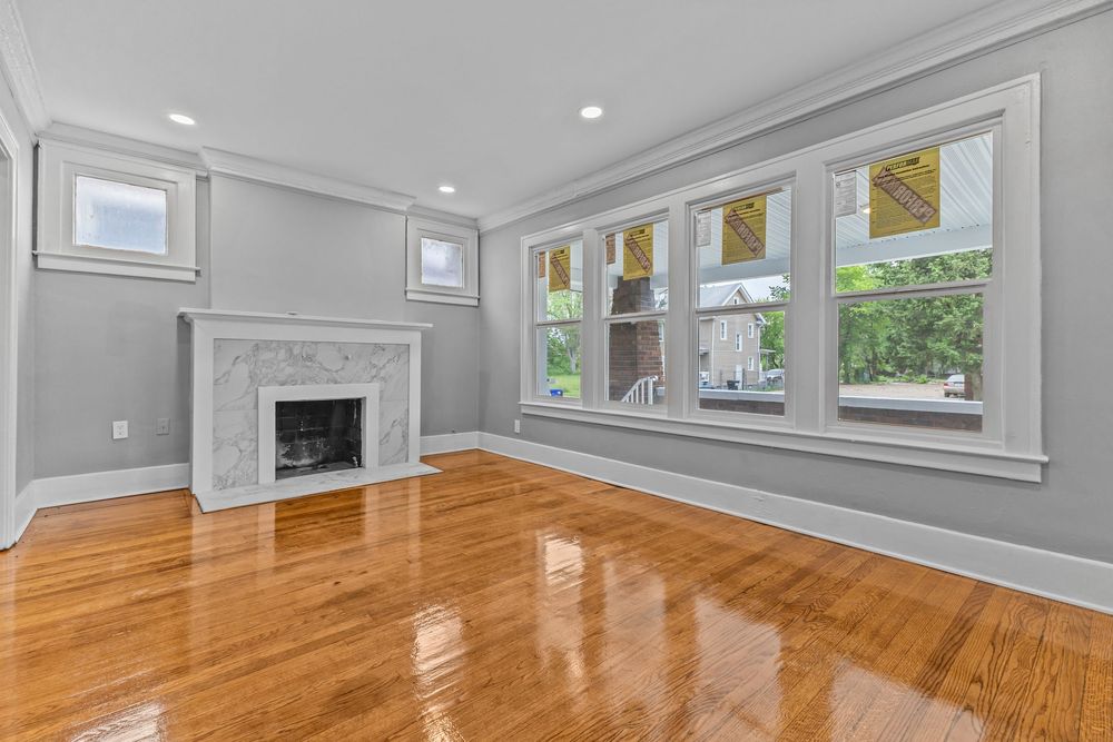 Bright living room with hardwood floors, marble fireplace, crown molding, and large windows in a classic home. Detroit Michigan Photo