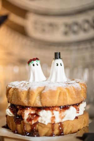 Halloween wedding cake topped with ghost bride and groom figurines on a cream-filled brioche stack.