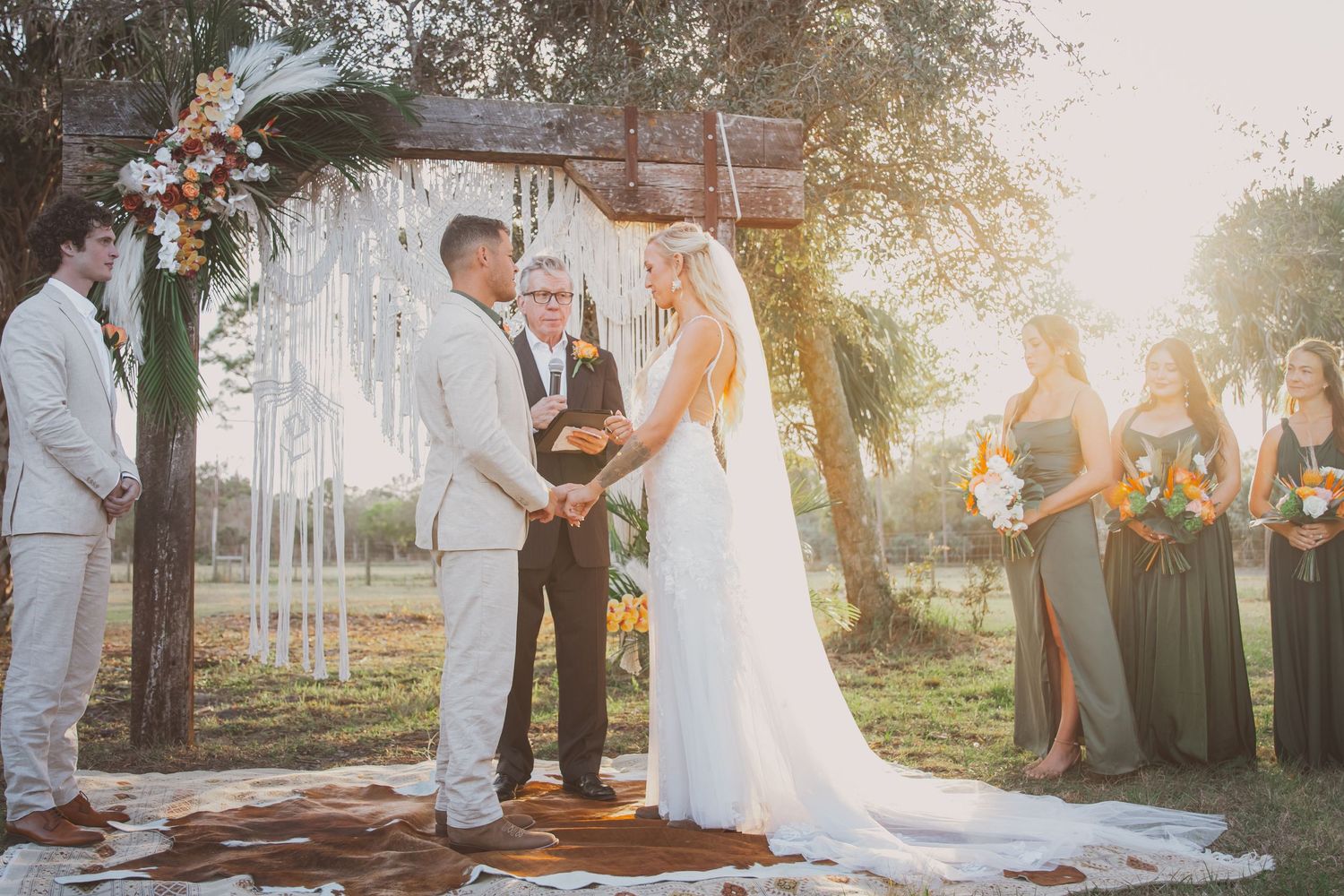 A bride and groom say their vows below a timber truss on a ranch with a coastal cowgirl aesthetic