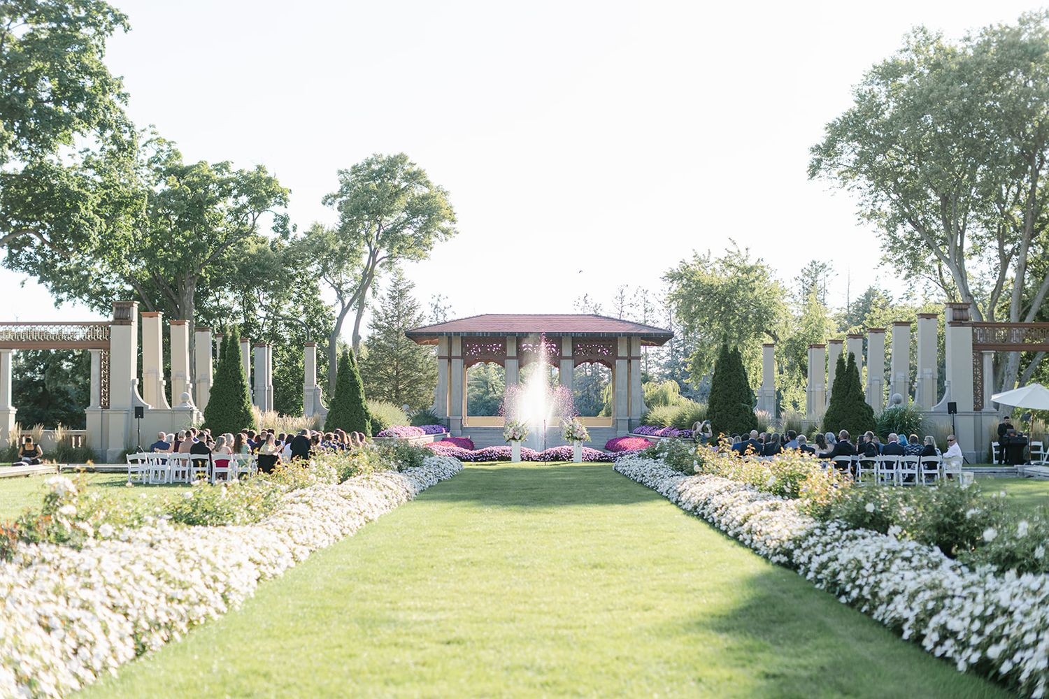 Armour House Wedding - Colorful garden bed with pink flowers and green shrubs near stone columns.