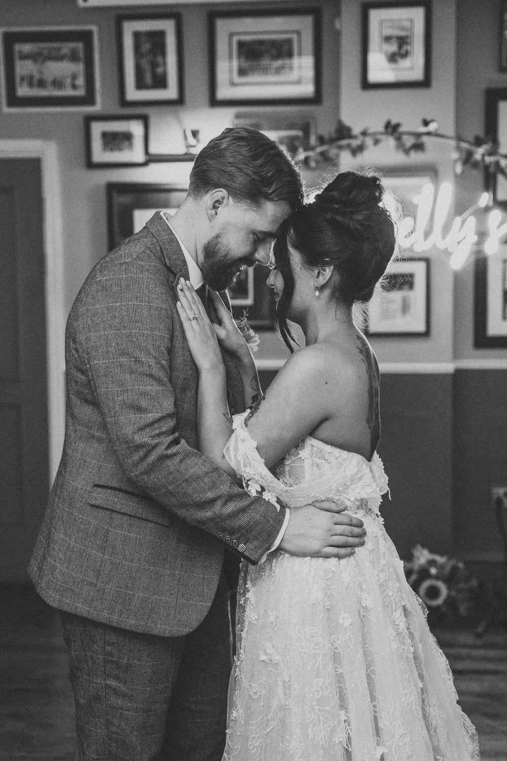 Black and white photo of bride and groom sharing an intimate moment during their first dance at wedding reception.